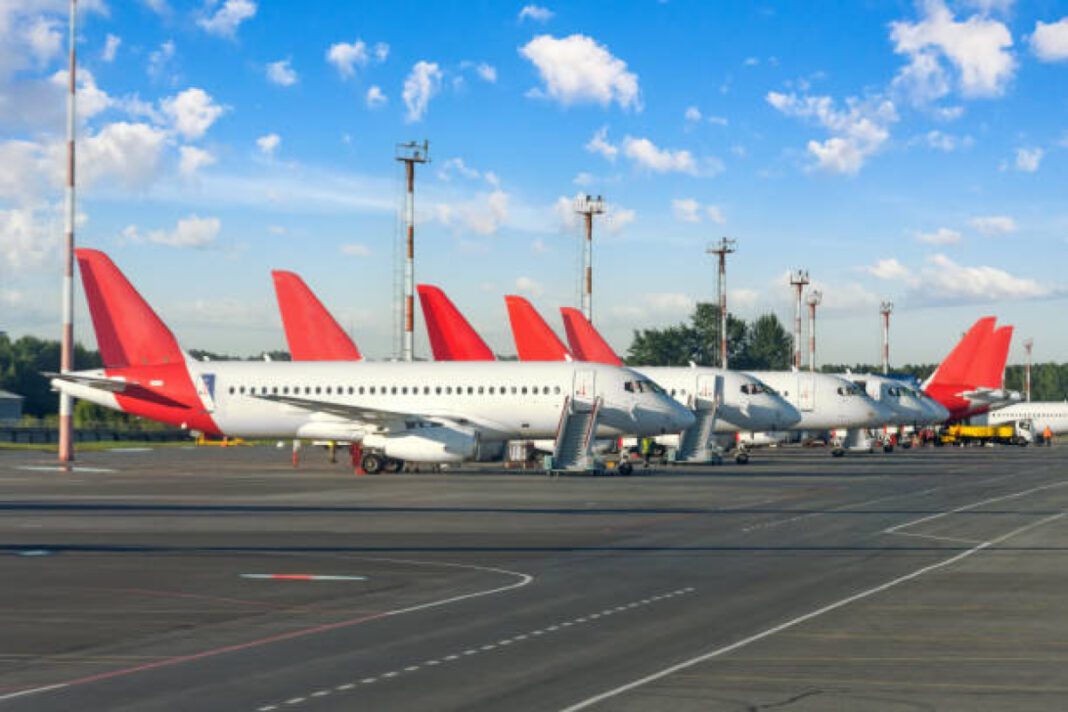Many identical jet planes in the airport parking lot in a row. Government, 12 airports, UDAN scheme, regional connectivity, affordable air travel, Regional Connectivity Scheme (RCS), accessibility, economic development, Ministry of Civil Aviation, aviation infrastructure, aviation sector growth